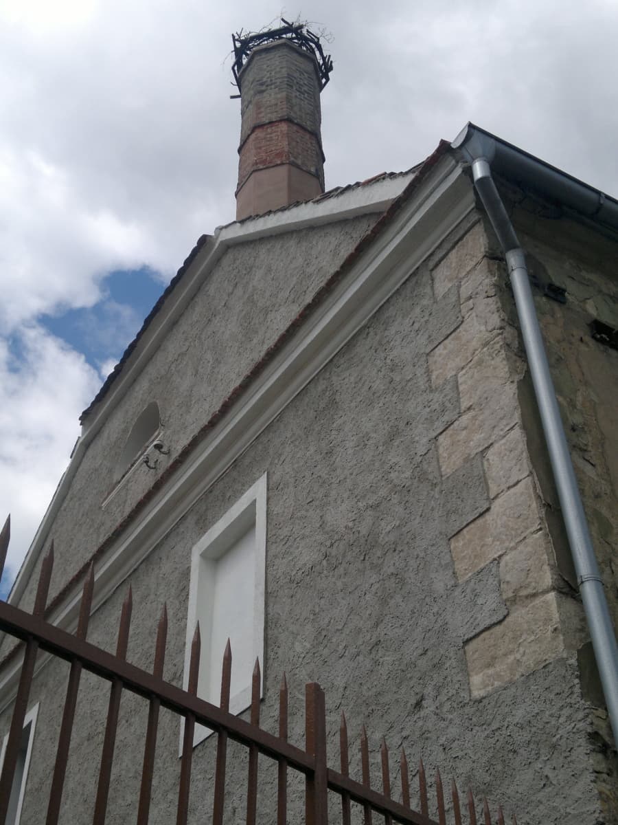 Opravený štít varny s novou omítkou, nad ním komín s podložkou pro čapí hnízdo.